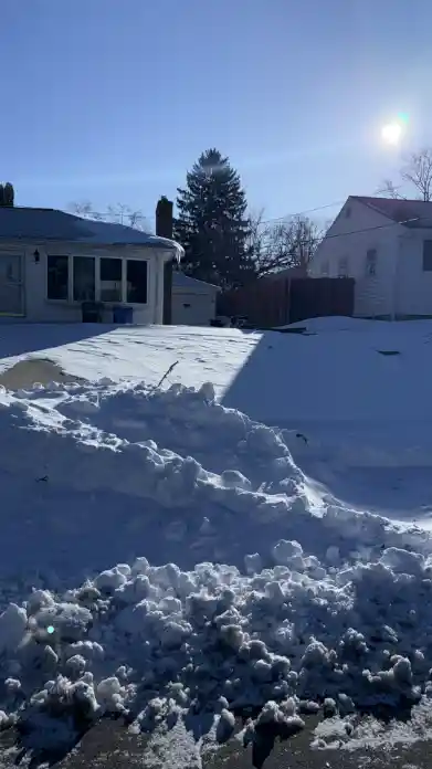 Snow-covered residential driveway before clearing